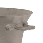 Close-up of a rounded side loop handle, flared rim and textured silver-coloured surface of the oval champagne cooler against white.