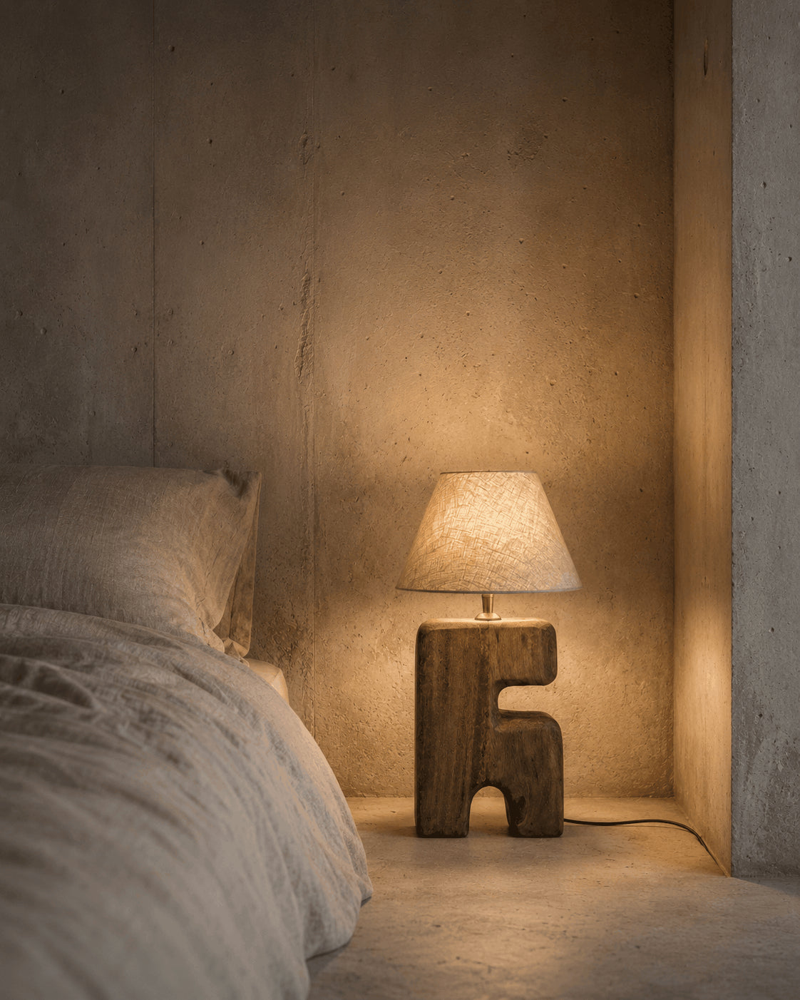 L’Objet Wooden Table Lamp – Brown, Small — lit beside a bed