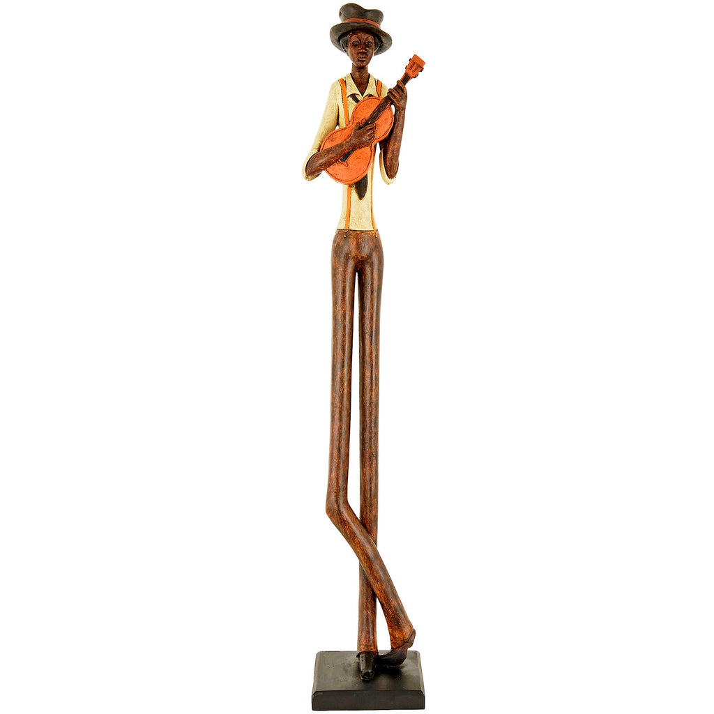 Full-length musician figurine against white, with elongated brown legs crossed near the ankles, a cream shirt, orange braces and a guitar on a dark rectangular plinth.