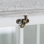 Close-up of the small antique-brass-coloured latch on the white lantern frame beneath the pale roof edge.