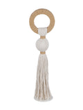 Front view of a natural-toned sculpture with a tan open loop, pale rounded rope centre and long tassel above a round pale base.