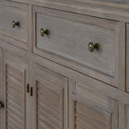 Close-up of a framed drawer front with two dark round knobs and fine grain lines above the louvred doors.