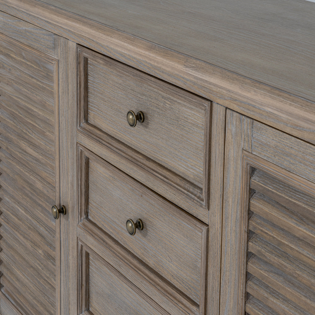Detail of the framed drawer fronts and round metallic-looking knobs between the louvred doors.