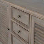 Detail of the framed drawer fronts and round metallic-looking knobs between the louvred doors.
