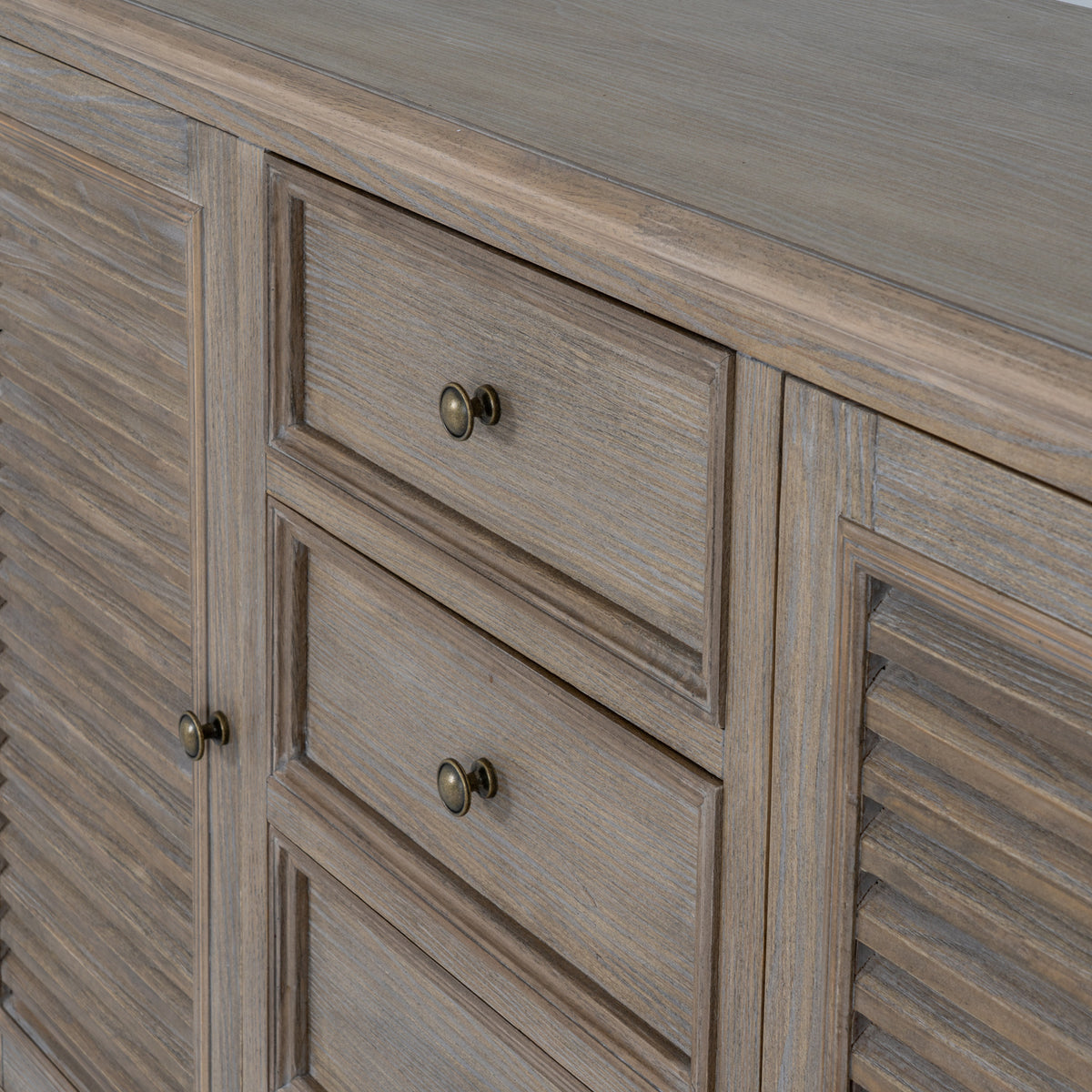 Detail of the framed drawer fronts and round metallic-looking knobs between the louvred doors.