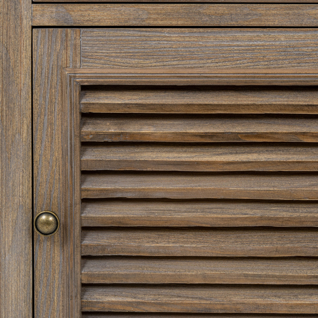 Close-up of the louvred door's horizontal slats, brown surface texture, surrounding frame and dark round pull.