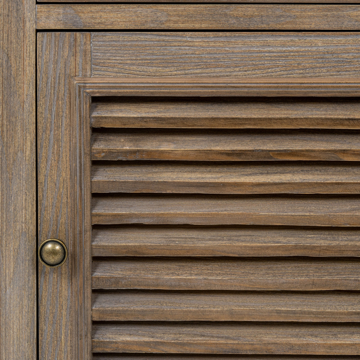 Close-up of the louvred door's horizontal slats, brown surface texture, surrounding frame and dark round pull.