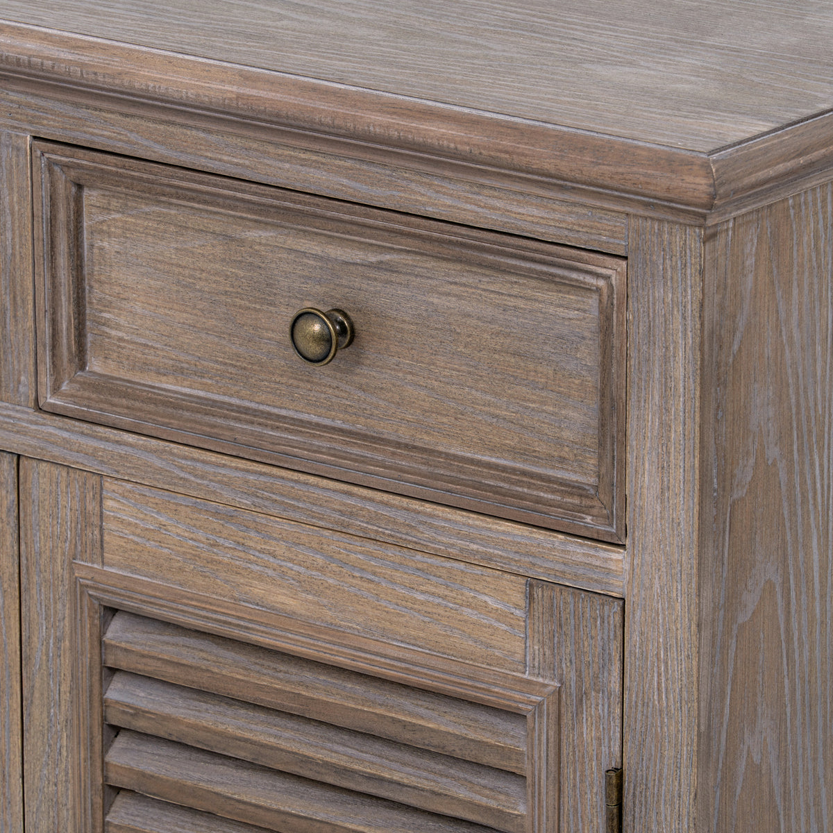 Detail of the closed drawer, rounded top edge and louvred door, with pale grain lines across the brown finish.