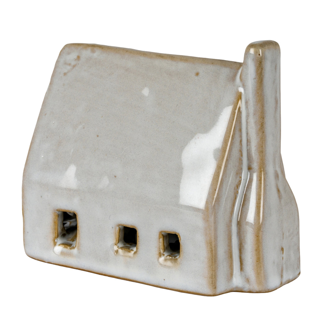Off-white barn-shaped decoration viewed at an angle, with three wall openings, a broad pitched roof and a rounded chimney on the right.