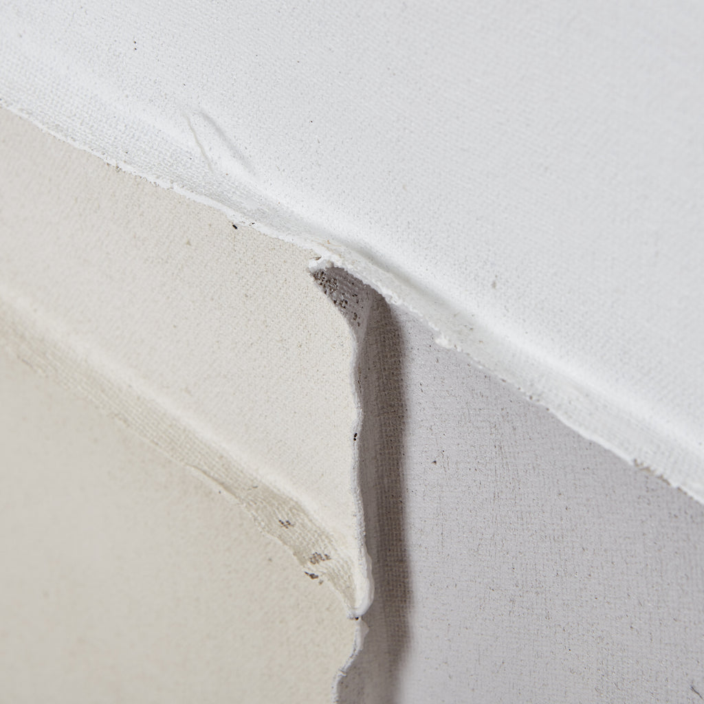 Surface detail where cream, grey and white areas meet, showing the canvas weave and curling raised edges.