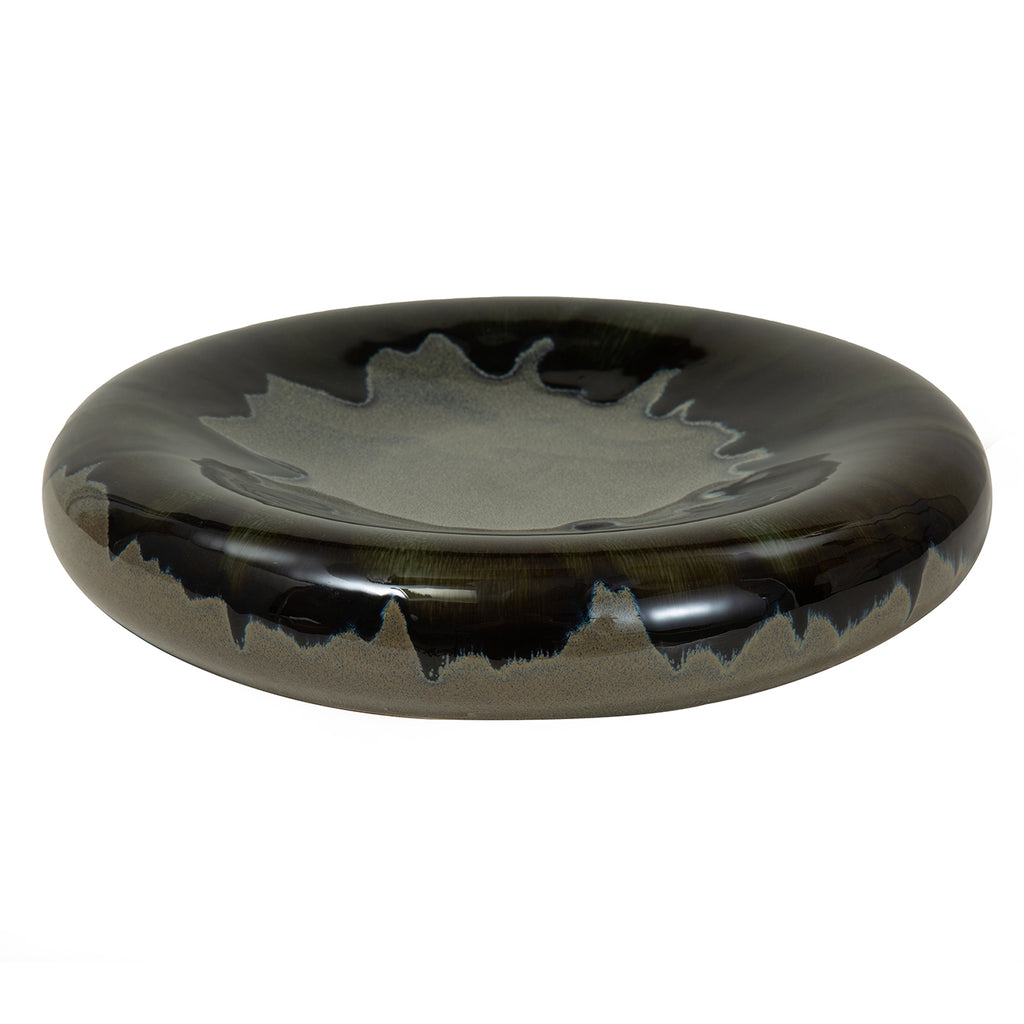 Angled view showing the bowl's shallow grey centre, rounded dark rim and irregular blue-black reactive glaze.