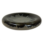Angled view showing the bowl's shallow grey centre, rounded dark rim and irregular blue-black reactive glaze.