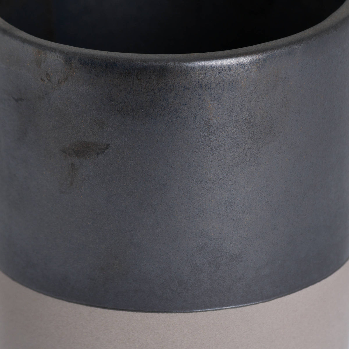 Close-up of the Lowband Planter showing its rounded rim, mottled metallic-grey surface and curved boundary above the pale lower band.