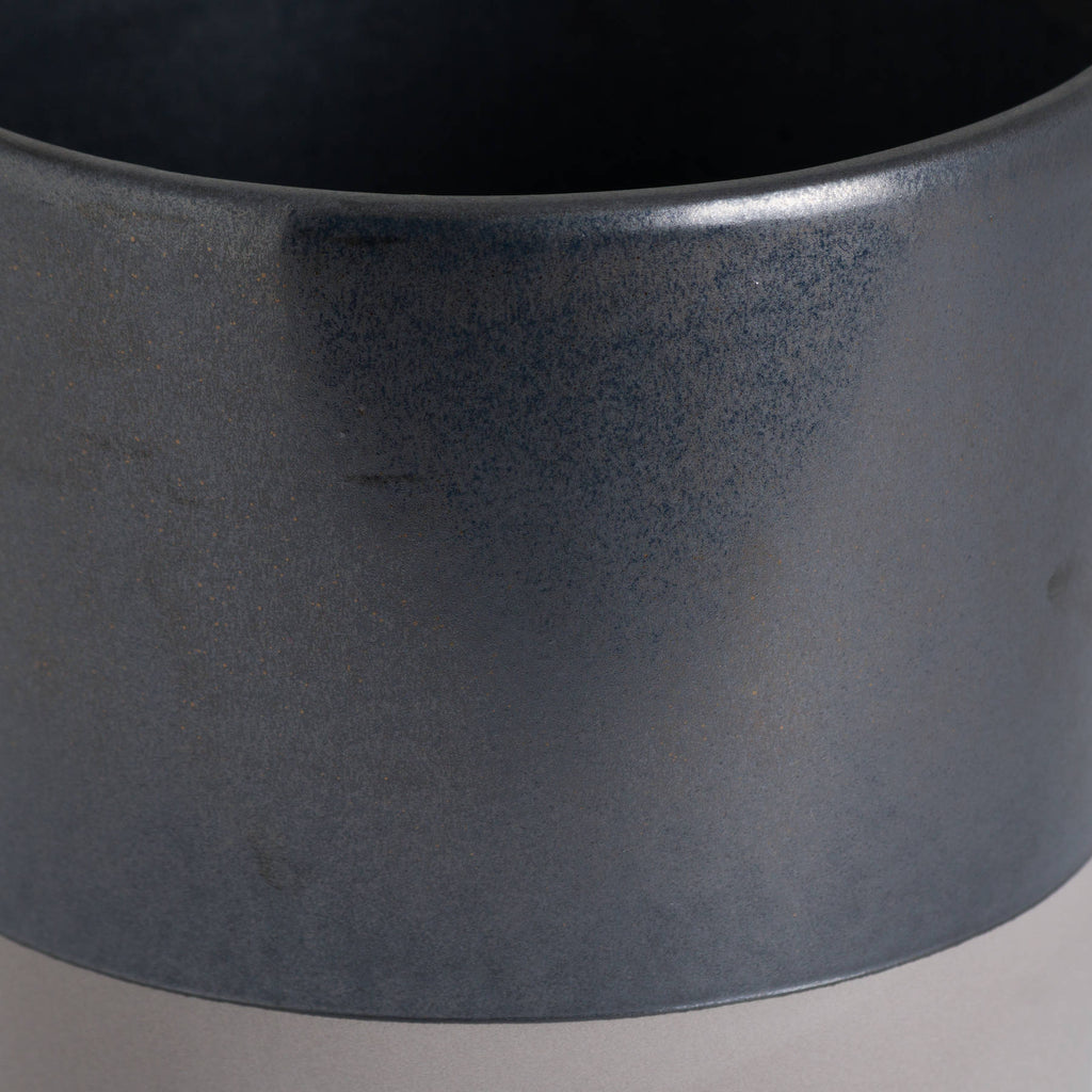 Close-up of the planter's finely mottled metallic-grey surface, curved rim and colour boundary above the pale band.
