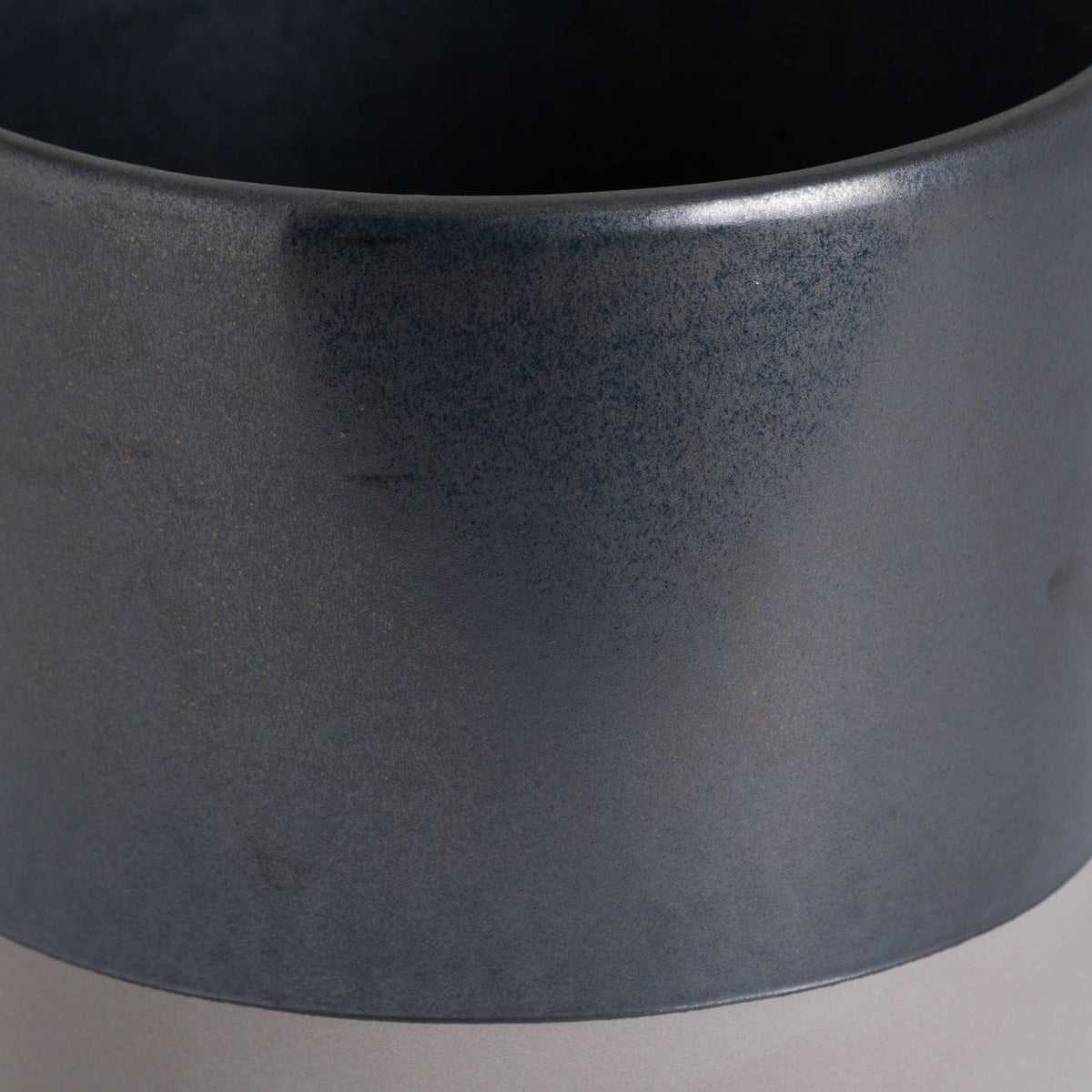 Close-up of the planter's finely mottled metallic-grey surface, curved rim and colour boundary above the pale band.