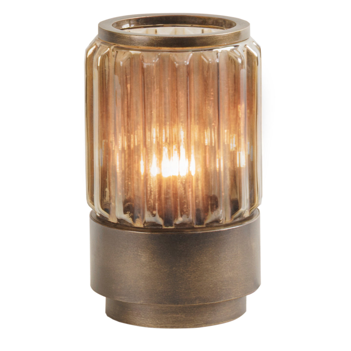 Lucent table lamp illuminated, with warm light glowing through fluted copper-brown glass above a bronze-gold base.