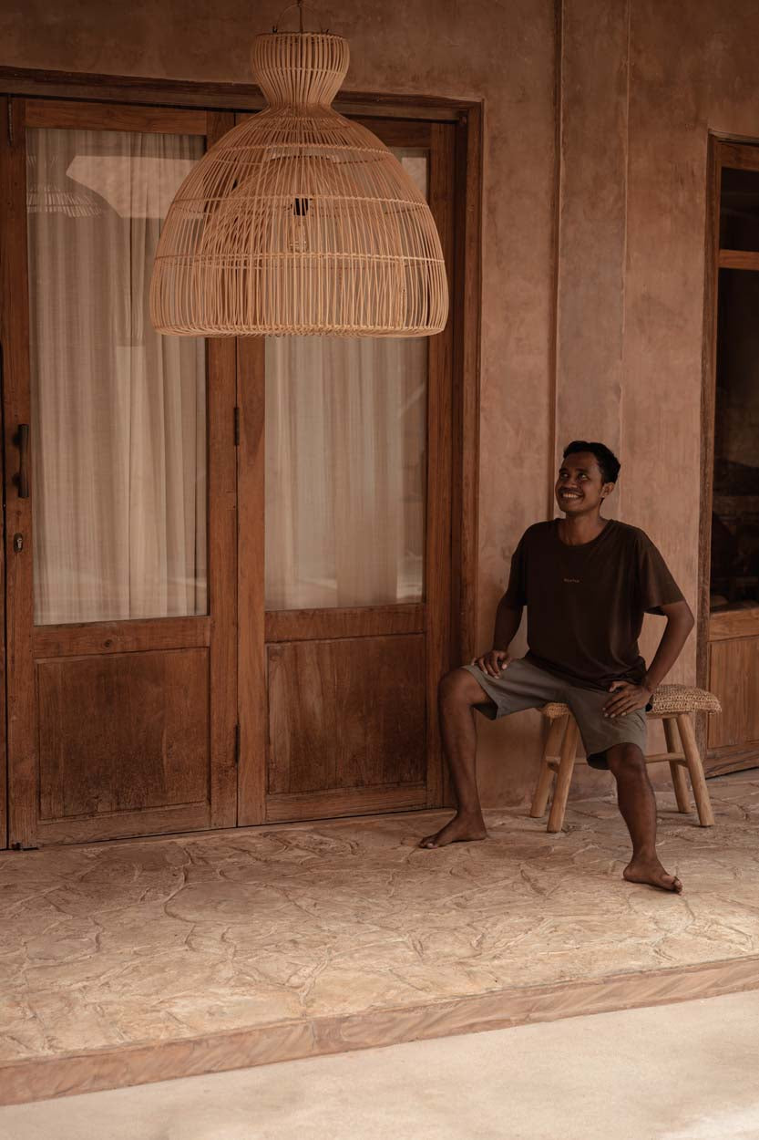 Matcha Whisk Rattan Pendant Light – Natural, Large – styled in a doorway with a seated person