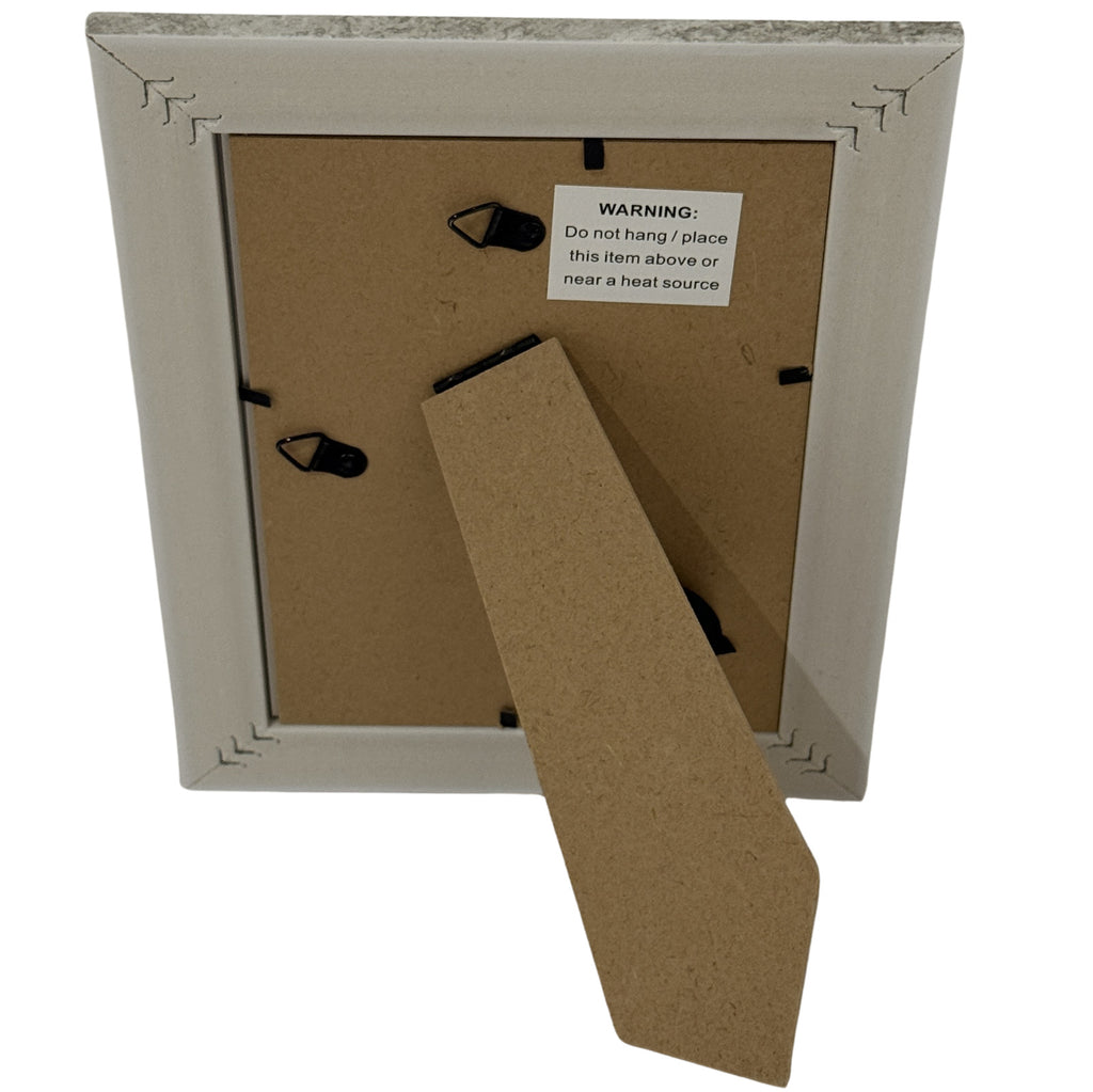 Rear view of the photo frame with its stand folded out, two hanging loops and a label warning against placement above or near a heat source.