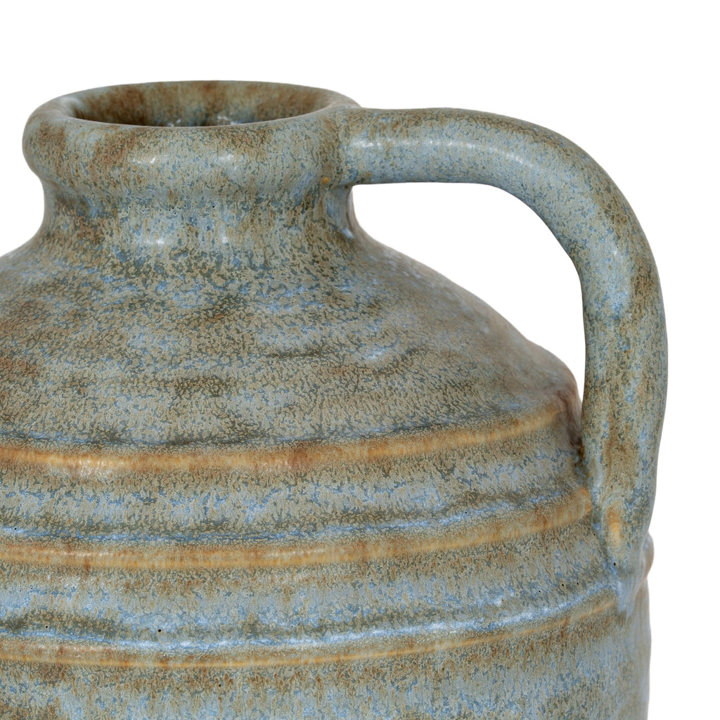 Close-up of the vase loop handle and rolled rim, with warm-brown ridges crossing the mottled blue-grey shoulder.