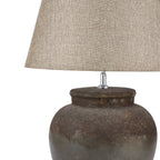 Close-up of the beige shade's weave-like texture above the broad pot lip and dark mottled surface of the lamp base.