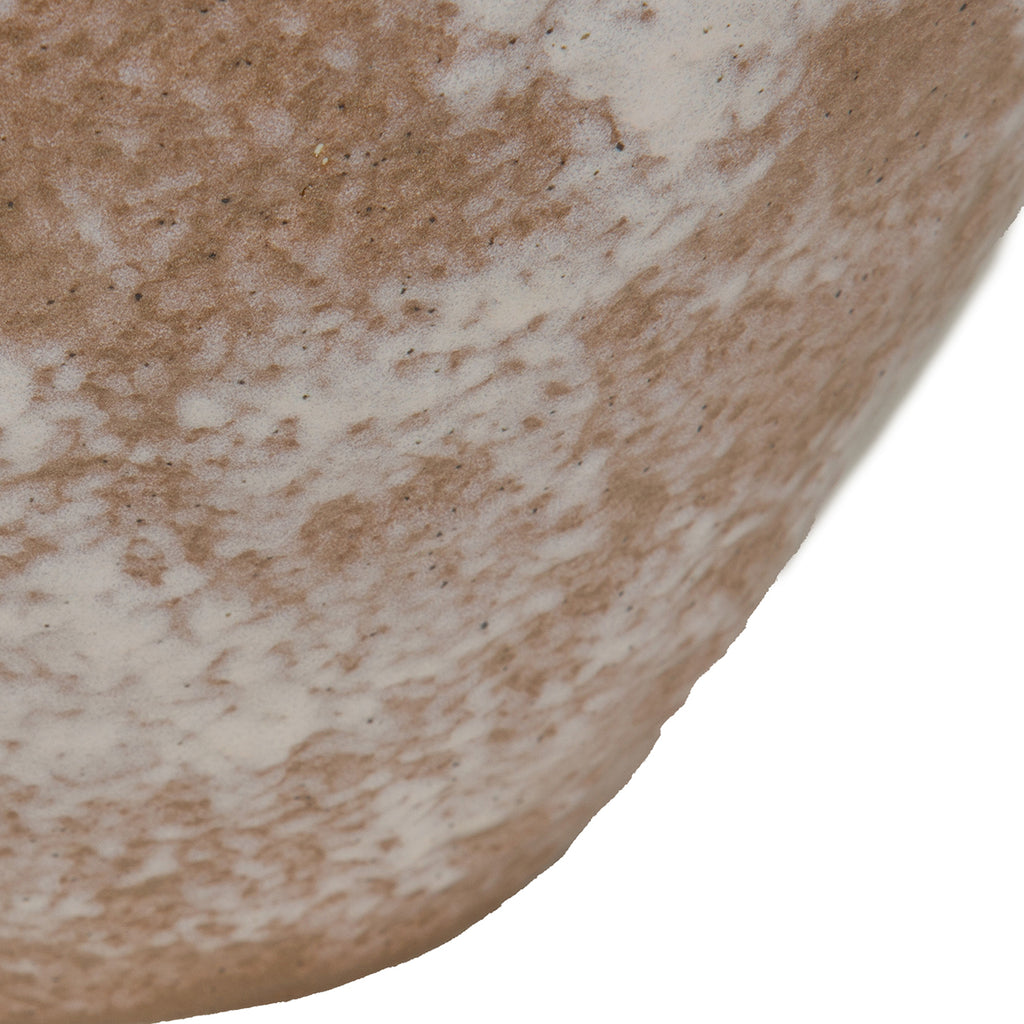 Close-up of the curved vase surface showing irregular ivory patches, earthy brown glaze and fine dark speckles.