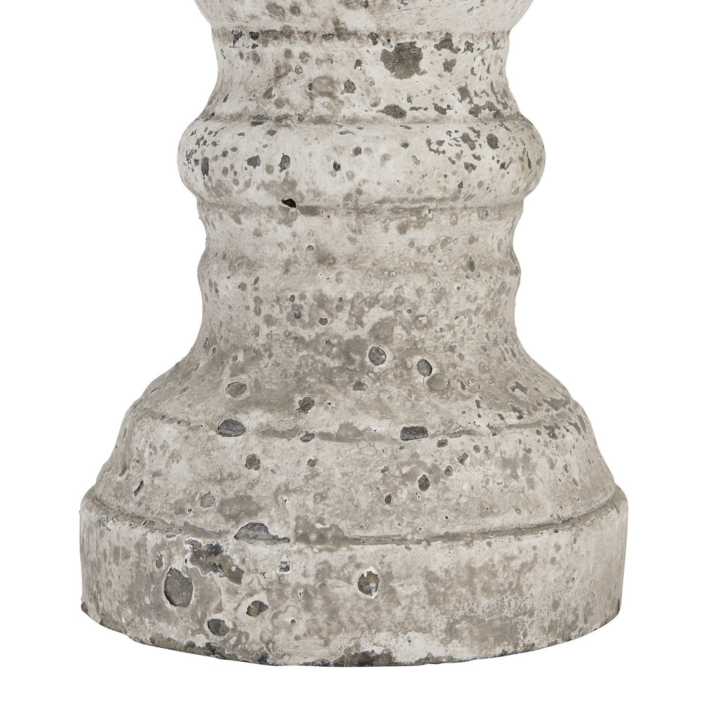 Detail of the candle holder's stepped round foot and lower curves, showing pits and rubbed patches across the pale surface.