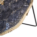 Close-up of the clock's gold-coloured outer edge beside the smoky stone face and black support.