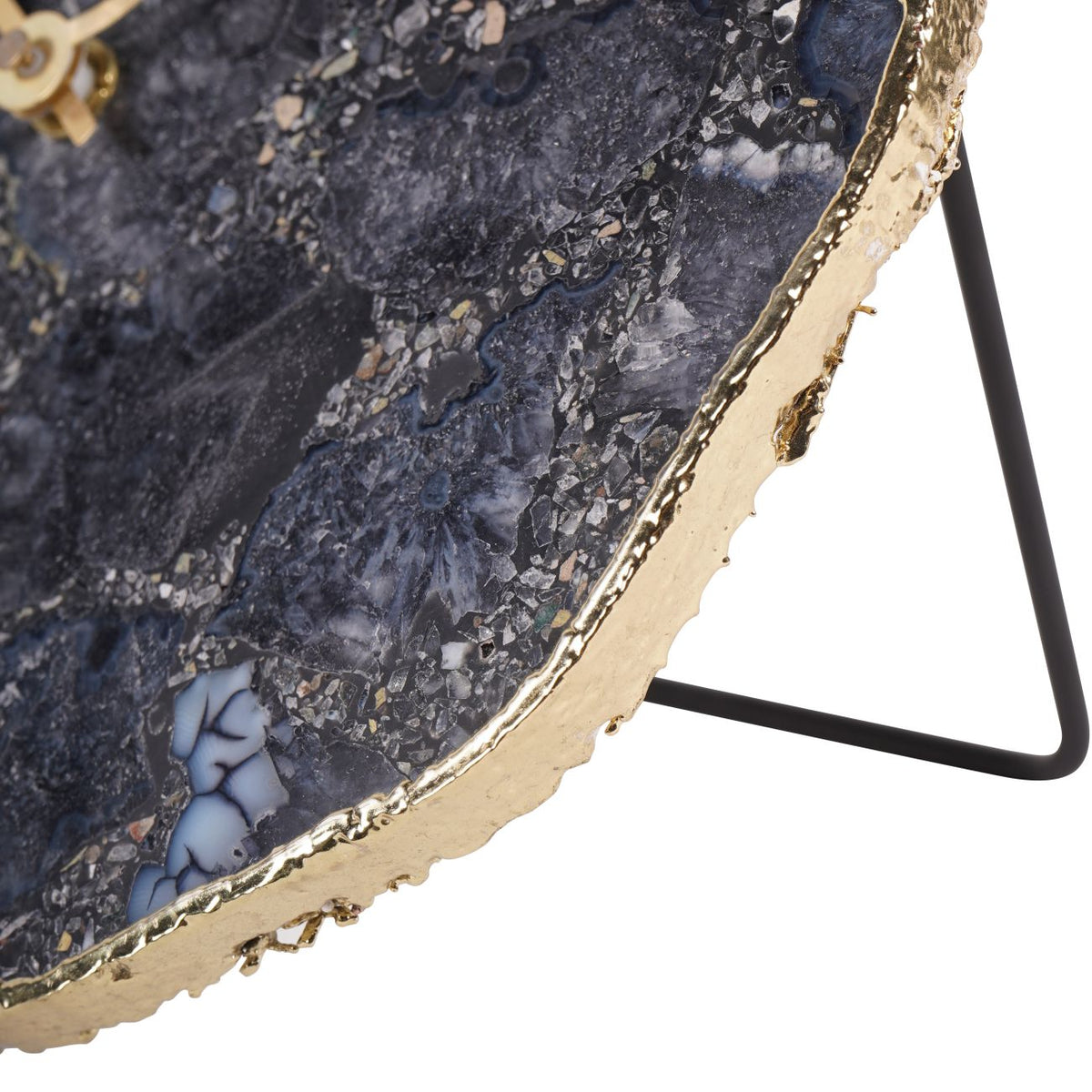 Close-up of the clock's gold-coloured outer edge beside the smoky stone face and black support.