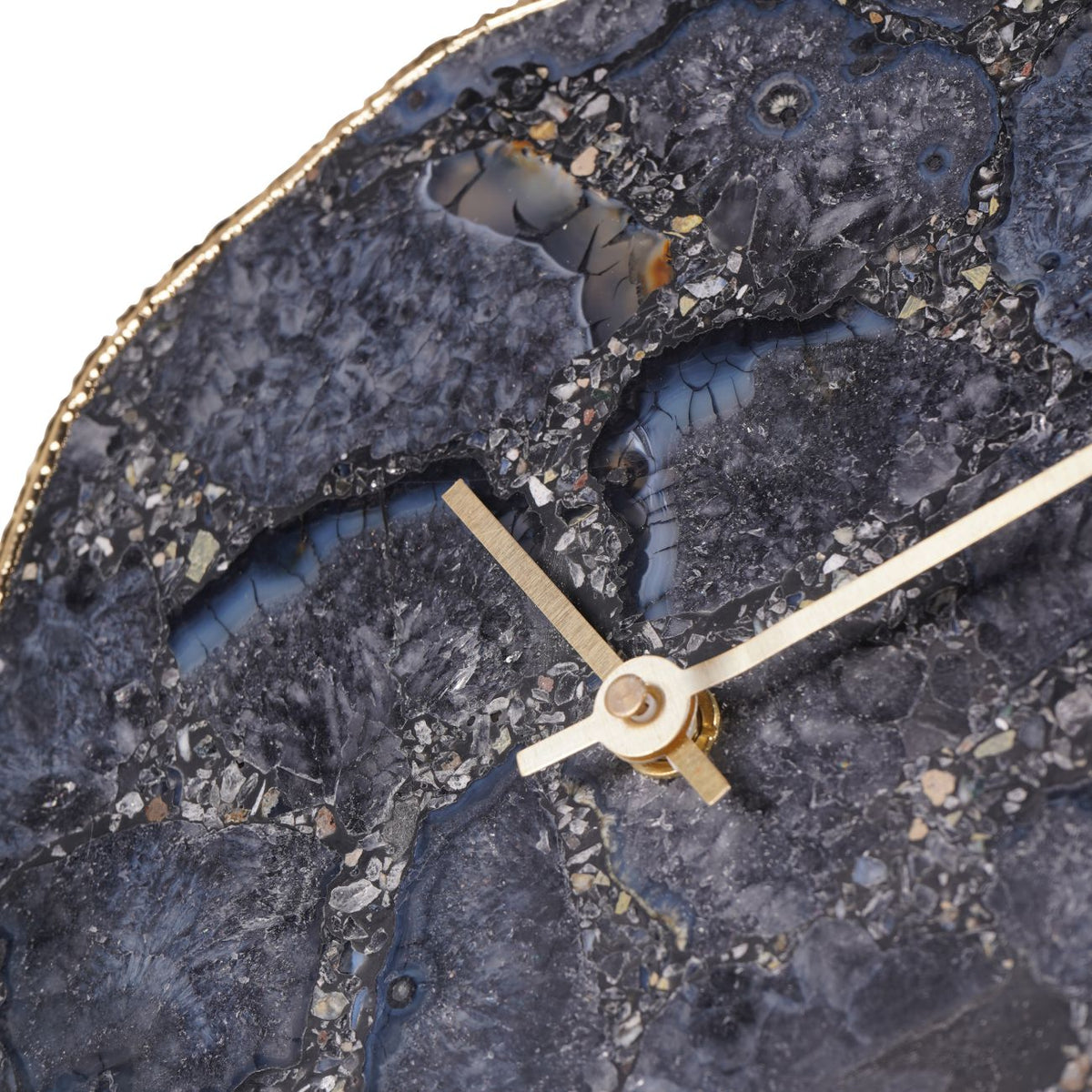 Detail of the clock hands against the agate face, showing dark mineral patterns and pale fragments.