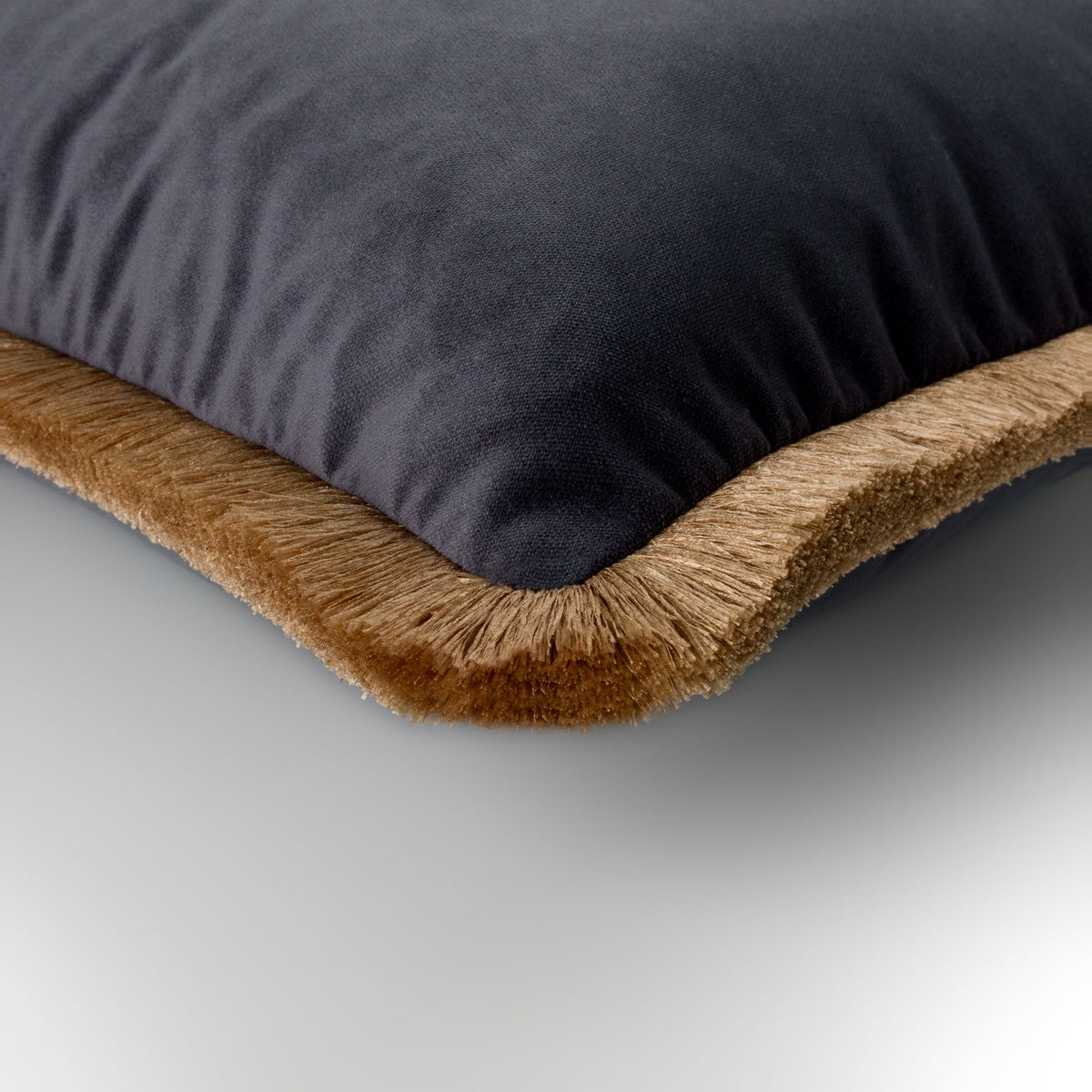 Close-up of the petrol-blue velvet Nerano Cushion with gold fringe
