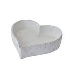 Single white heart-shaped dish viewed at an angle, showing its open interior, low walls and rough rim.