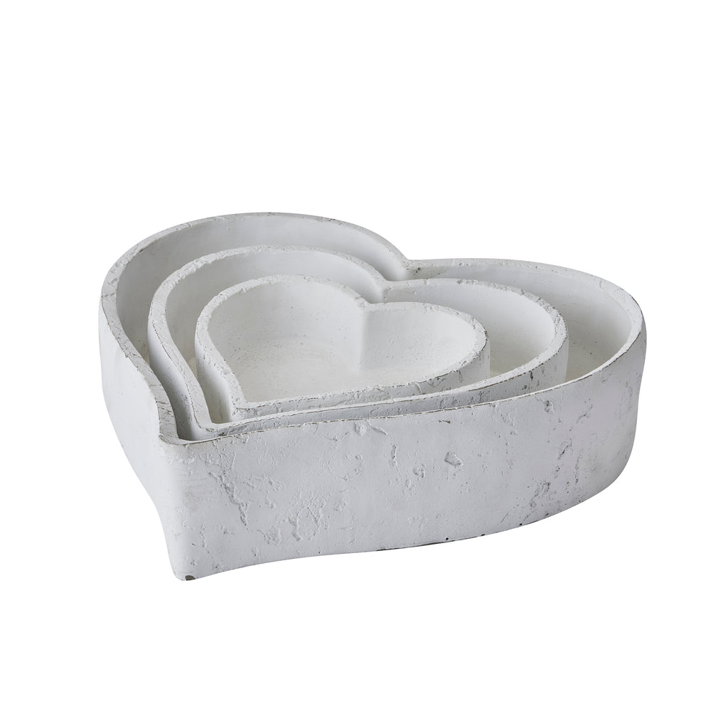 Three white heart-shaped dishes nested together, showing layered rims and a rough matt exterior.