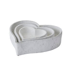 Three white heart-shaped dishes nested together, showing layered rims and a rough matt exterior.
