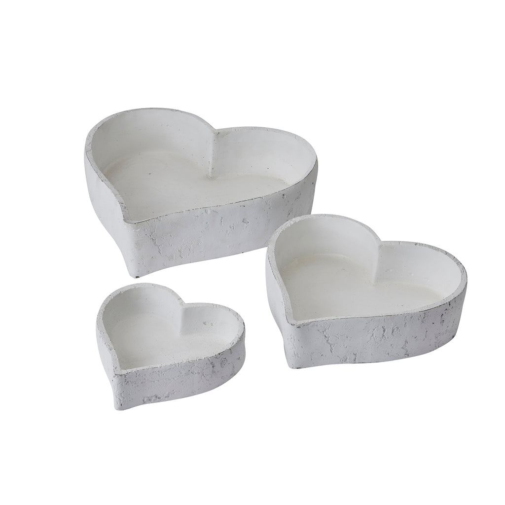 Three graduated white heart-shaped dishes displayed separately, with open interiors and textured outer walls.