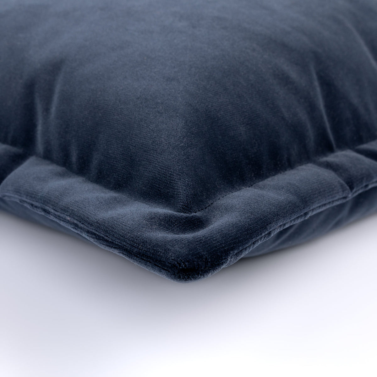 Angled close-up of the navy velvet Noctra Cushion with its piped edge