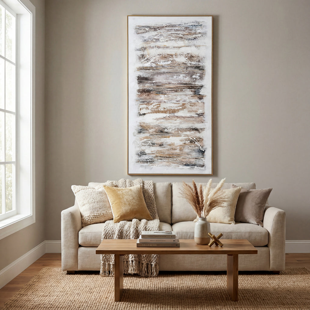 Ochre abstract framed artwork displayed above a cream sofa with neutral cushions and a knitted throw, behind a wooden coffee table.