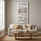 Ochre abstract framed artwork displayed above a cream sofa with neutral cushions and a knitted throw, behind a wooden coffee table.