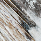 Oblique detail of the abstract surface showing fine ochre lines, white splashes, dark brown patches and visible texture.