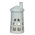 Front view of a white lighthouse tea light holder with three tiers of cut-out windows, a conical roof and an offset chimney.