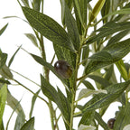 Close-up of a dark olive-like fruit among pointed green artificial leaves with pale vein patterns and lighter undersides.