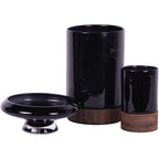 Large black hurricane vase beside a smaller vase on a wooden base and a low black pedestal bowl.