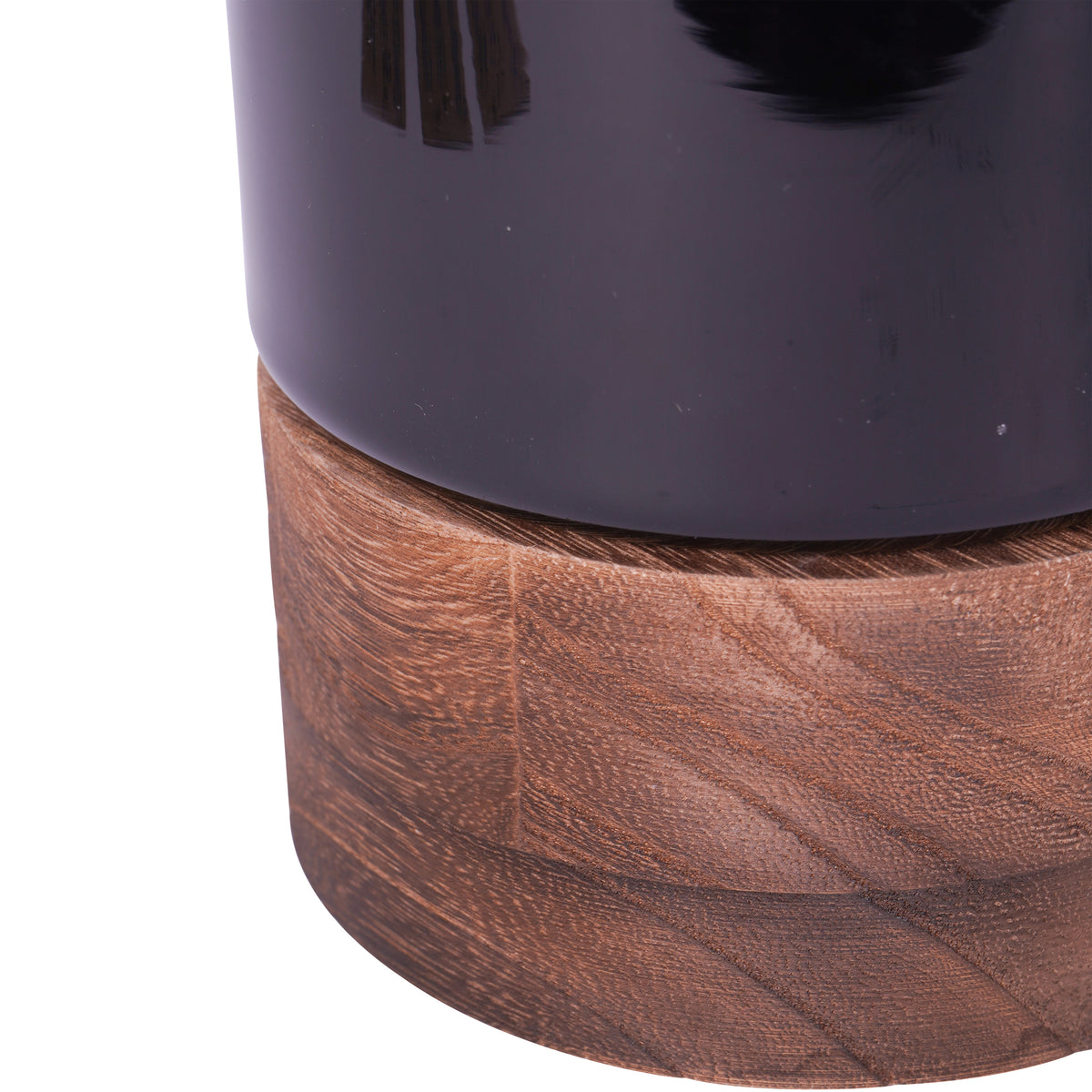 Close-up of the black glass vessel resting on its brown wooden base, showing the wood grain.