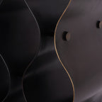 Close-up of the wine rack's dark metal surface, warm bronze-coloured curved edge and round connector end.