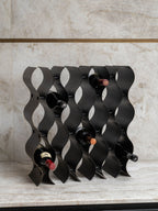 Upright wine rack holding five bottles on a pale stone counter against a matching stone wall.