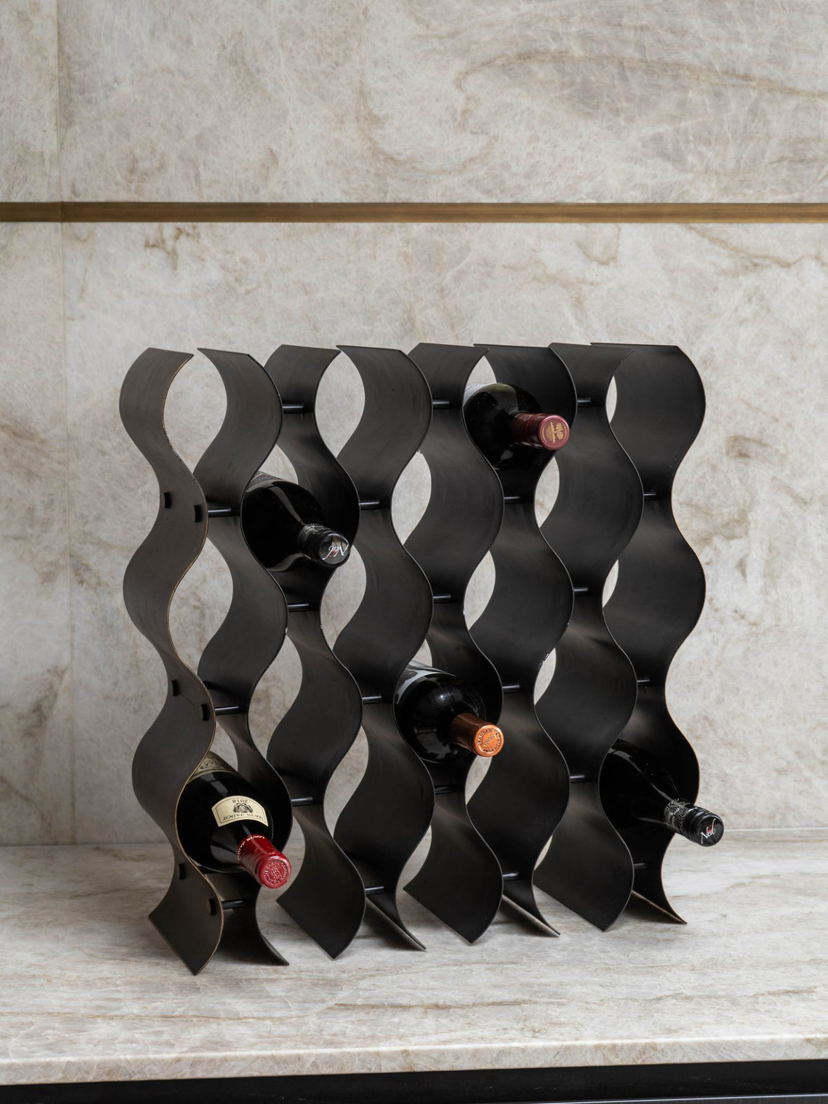 Upright wine rack holding five bottles on a pale stone counter against a matching stone wall.