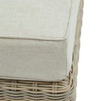 Close-up of the pale cushion's textured fabric and piped corner above the curved weave of the footstool base.