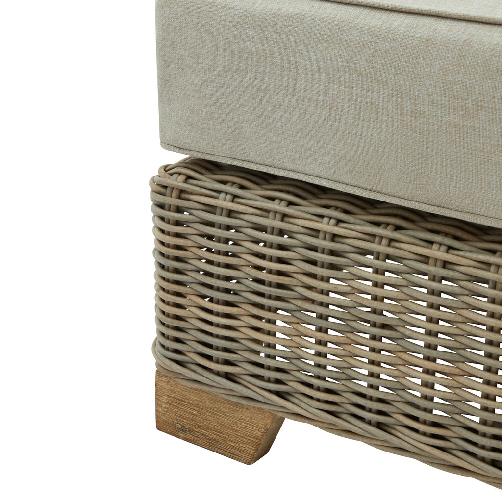 Detail of the footstool's open grey weave beneath the pale cushion, with a short wood-grain-effect foot visible below.
