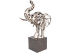 Angled view of a silver-coloured openwork elephant-head sculpture with a raised trunk, curved tusks and broad ears on a black plinth.