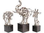 Silver-coloured openwork elephant-head sculpture in the centre, flanked by feline and giraffe head sculptures, each on a dark plinth.