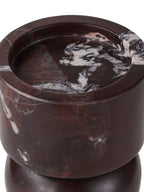 Close-up of the recessed candle seat and polished burgundy rim, with broad pale markings across the marble.